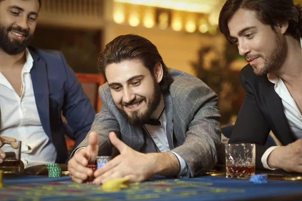 Group man gambler in a suit at table roulette playing poker at a casino.