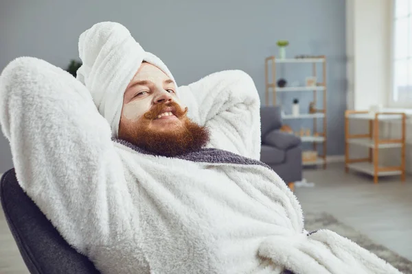 Conceito de cosmetologia máscara de beleza pedicure engraçado. Homem gordo engraçado em um roupão de banho e toalha faz procedimento de spa no salão — Fotografia de Stock