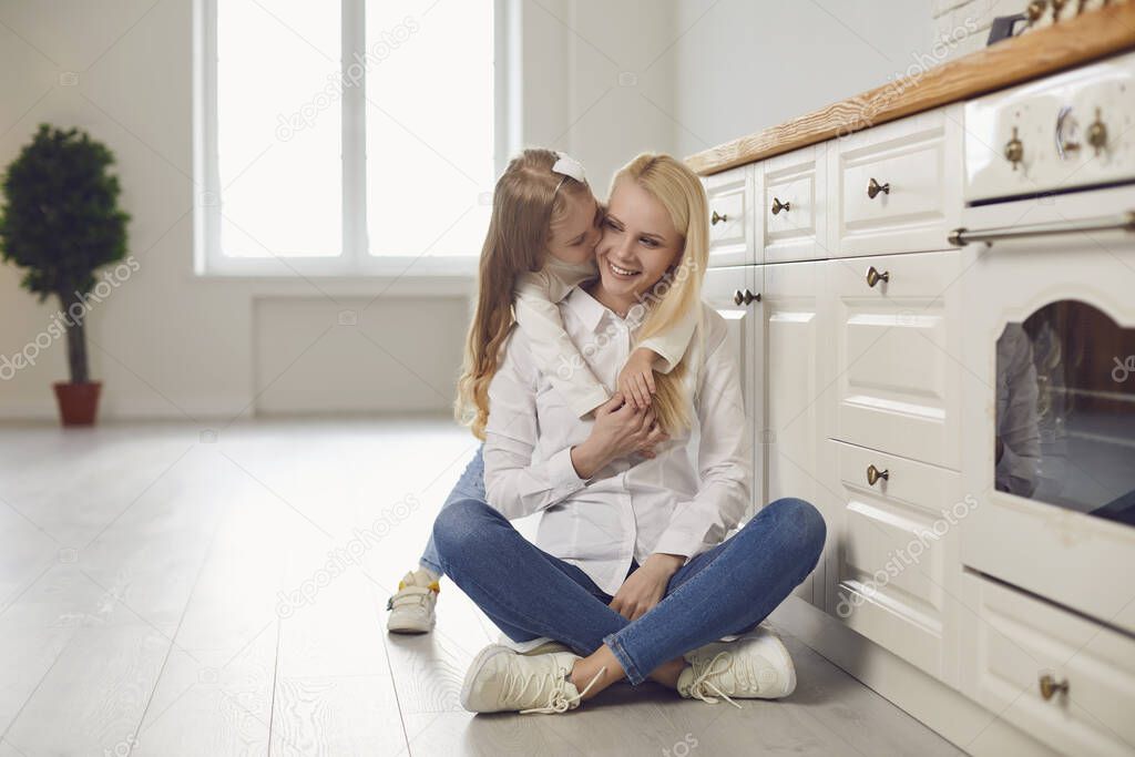 Happy mothers day. Mother and daughter hugging smiling in the kitchen.