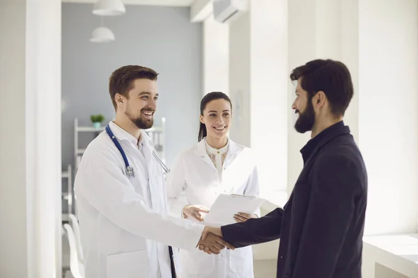 Händedruck. Praxisarzt und Patient schütteln lächelnd Hände in der Klinik. — Stockfoto