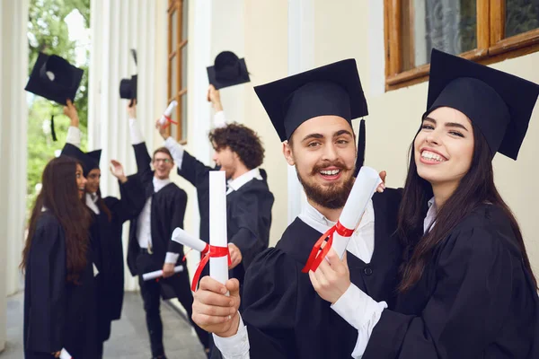 Graduadas con diplomas en sus manos abrazándose — Foto de Stock