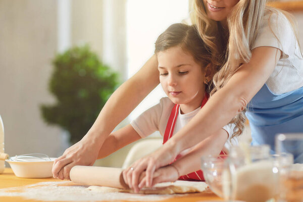 Мать и дочь готовят муку хлебобулочных изделий на столе на кухне. С Днем матери
