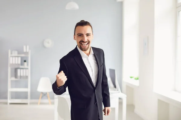 Un homme d'affaires vêtu d'une veste noire croise les bras en souriant au bureau — Photo