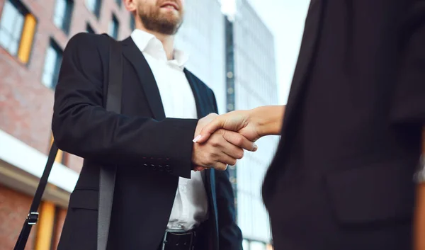 Une poignée de main. Homme d'affaires et femme d'affaires se serrent la main tout en se tenant debout à l'extérieur dans un bâtiment d'affaires . — Photo