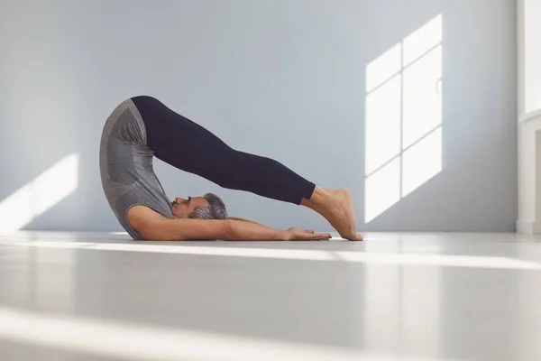 Hombre del yoga. Un hombre está practicando el equilibrio del yoga en una habitación gris. —  Fotos de Stock