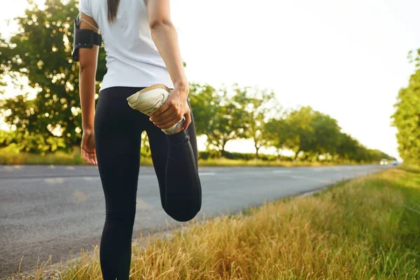 Молодая спортсменка согревает ногу перед тренировкой на открытом воздухе . — стоковое фото