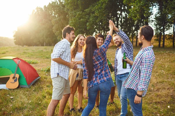 Young people are smiling cheerfully while standing on the grass on picnic — Stock Photo, Image