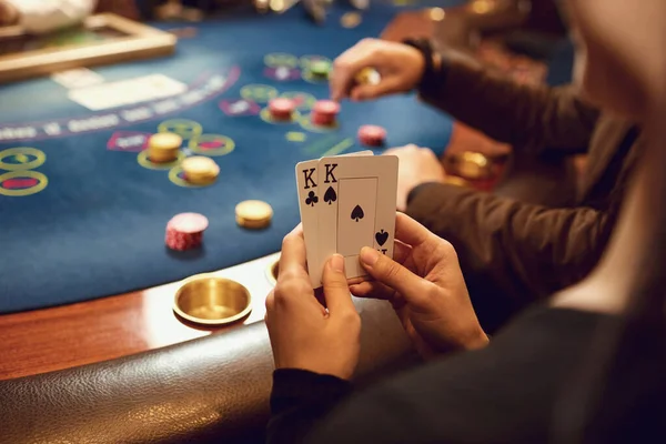 Mãos fechadas de um jogador de poker verificando cartas em um cassino . — Fotografia de Stock