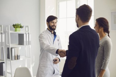 Kendine güvenen doktor ve klinikteki masada oturan çift hasta. Aile doktoru.