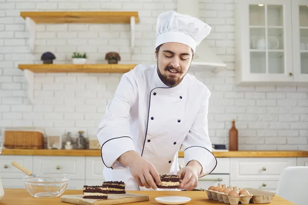 Erkek bir pasta şefi mutfak fırınında pasta süslemeye çalışıyor. — Stok fotoğraf