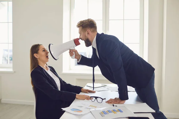 Boss businessman shouting in magaphone at businesswoman employee secretary at desk in office — Stock Photo, Image