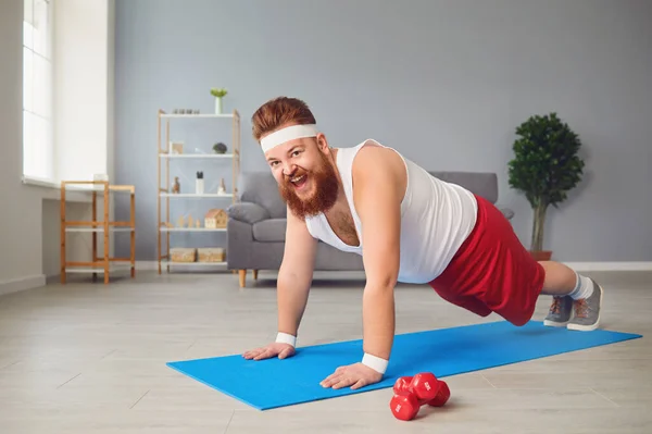 Hombre gordo divertido haciendo ejercicios en el suelo sonriendo en el suelo en casa . — Foto de Stock