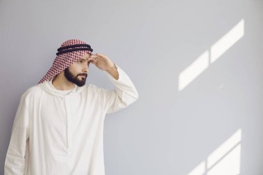 Çekici gülümseyen Arap adam Gri bir arka plana bakıyor