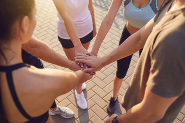 Spor yapan bir grup insan parkta el ele tutuşuyor..