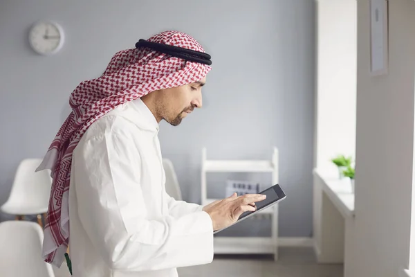 Арабский мужчина использует планшет для работы в офисе в Интернете . — стоковое фото