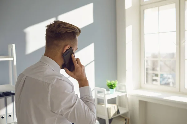 Homme formel parlant sur smartphone dans un bureau ensoleillé — Photo