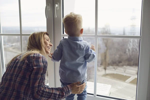 Καραντίνα στο σπίτι. Οικογένεια σε καραντίνα στο δωμάτιο. Μητέρα και μωρό κοιτάζουν έξω από το παράθυρο από το σπίτι.. — Φωτογραφία Αρχείου
