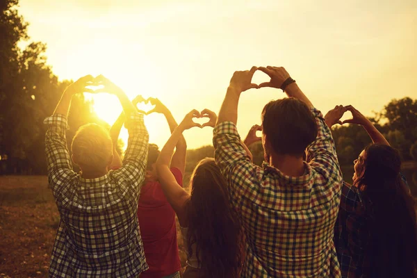 Hart teken met de handen van een groep mensen bij zonsondergang. — Stockfoto