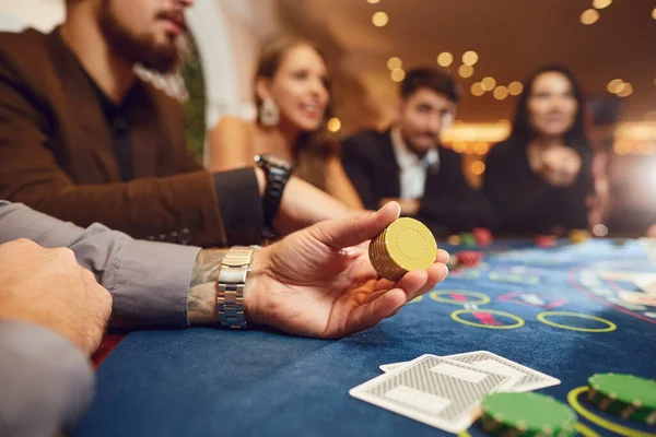 Chips in the hands of a male roulette player in casino background.