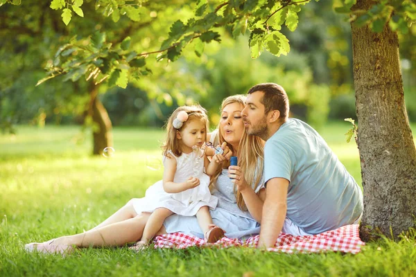 Lycklig familj kramas medan man sitter i parken. — Stockfoto