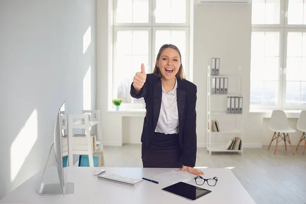 Mujer de negocios sonriente levantó el pulgar mientras estaba sentada en una mesa en la oficina . — Foto de Stock