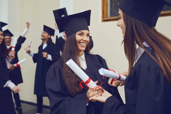 Vrouwelijke afgestudeerden met diploma's in hun handen knuffelen — Stockfoto