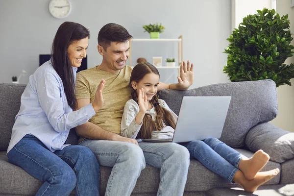自宅のソファで子供と一緒に座っている間、ラップトップを使用して幸せな家族のオンライン通信 — ストック写真