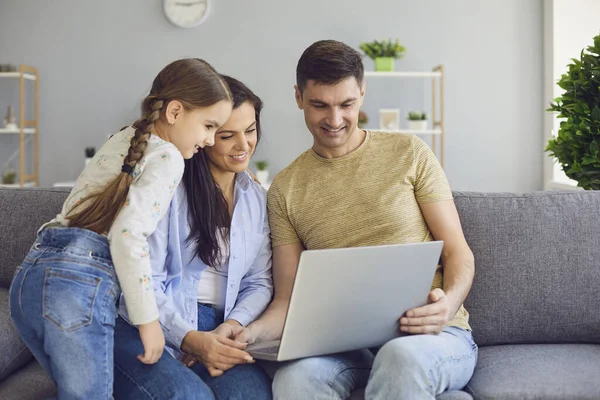 Щасливі сімейні балачки онлайн за допомогою ноутбука, сидячи з дитиною на дивані вдома . — стокове фото