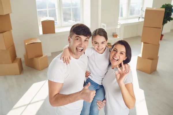 Lycklig familj med nycklar i händerna står i ett nytt hus. — Stockfoto