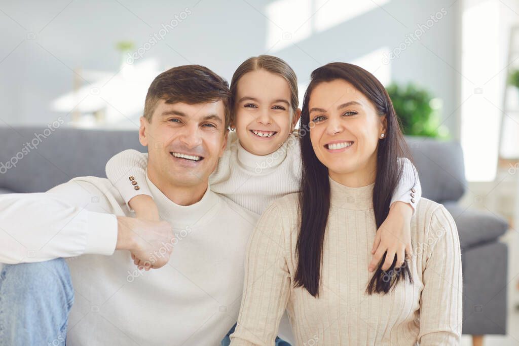 Happy smiling family. Daughter mother and father smiling hugging cheerful in a room at home.