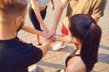 Spor yapan bir grup insan parkta el ele tutuşuyor..