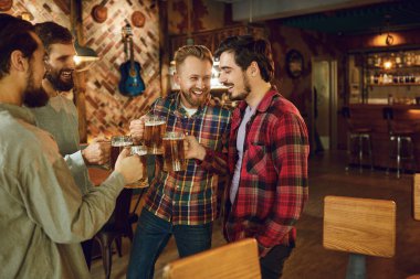 Bir spor barında bardakları birayla tokuşturan bir grup mutlu arkadaş..