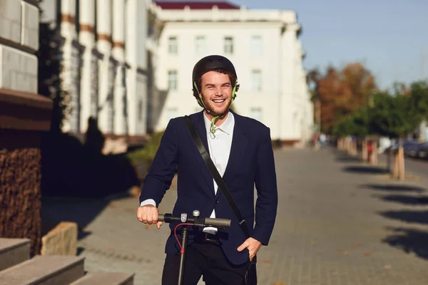 Joven en un casco monta un scooter eléctrico en una calle de la ciudad en verano — Foto de Stock