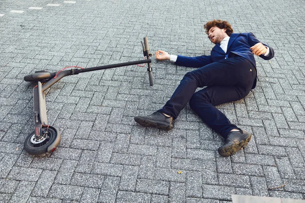 Accidente con un scooter eléctrico. Un hombre cayó de un scooter en una calle de la ciudad . — Foto de Stock