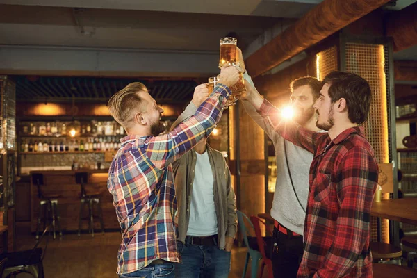 Group of happy friends clinking glasses with beer at a sports bar. — 스톡 사진