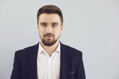 Gri arka planda, rahat ceketli, kafası karışık, güvensiz bir adam. Duyguların ifadesi