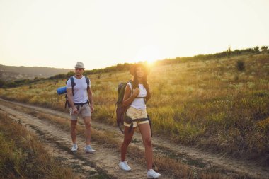 Sırt çantalı çift güneşin batışında doğa yürüyüşünde.