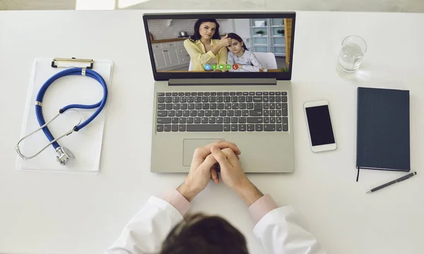 Online gyerekorvos. Doktor a vonalban. A terapeuta otthon ülő laptoppal konzultál a családanyjával és a lányával. Felülnézet. — Stock Fotó