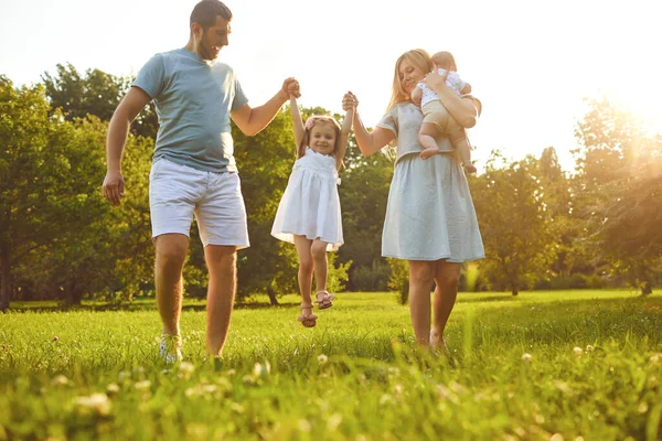 Família feliz com crianças no parque ao pôr do sol. — Fotografia de Stock