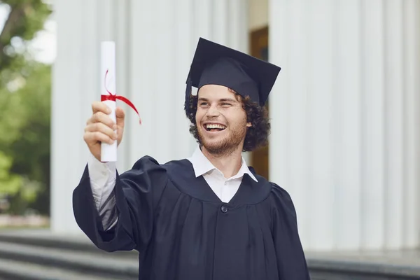 Egy fiatal férfi diplomával mosolyog az egyetemi diplomások. — Stock Fotó