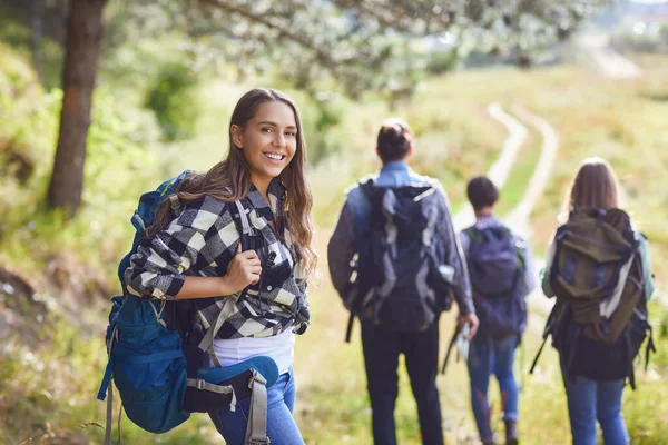 Dívka s batohem s přáteli, turisté procházky v přírodě. — Stock fotografie