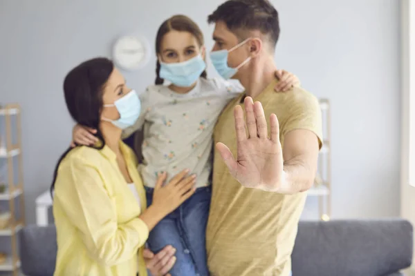 自宅の部屋に立っていると、顔に医療用マスクの家族がカメラを見ている。父はウイルス感染の脅威から家族を守るという概念を提唱します. — ストック写真