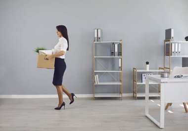 Ofisinde karton kutu olan işsiz kadın işçi yeni bir iş aramak için ayrılıyor..