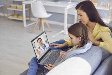 Çevrimiçi doktor. Çevrimiçi bir erkek doktor, anne ve kızına bilgisayarla görüntülü sohbet yoluyla semptom teşhisi koyuyor..