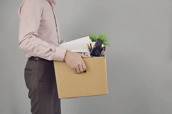 Безработица. Увольнение. Уволенный бизнесмен расстроен картонной коробкой, стоящей на сером фоне копирайта. Пособия по безработице . — стоковое фото