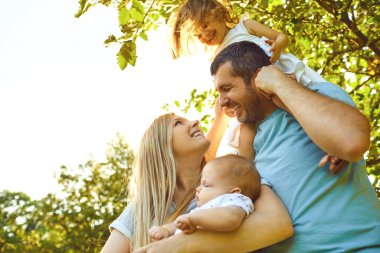 Happy parents with children in the park at sunset.