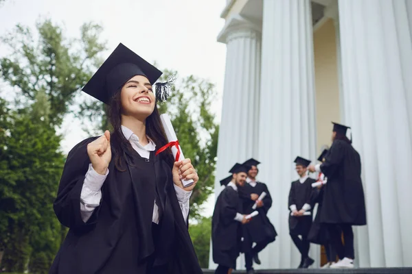 Een meisje afgestudeerd tegen de achtergrond van universitaire afgestudeerden. — Stockfoto
