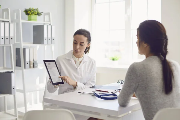 Una paciente visitando a una doctora en el consultorio. Trabajo médico escribe una receta en una mesa en un hospital . —  Fotos de Stock