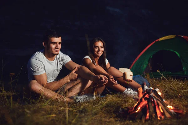 Mladý pár turisté na táboření noc vařit chléb u táboráku — Stock fotografie