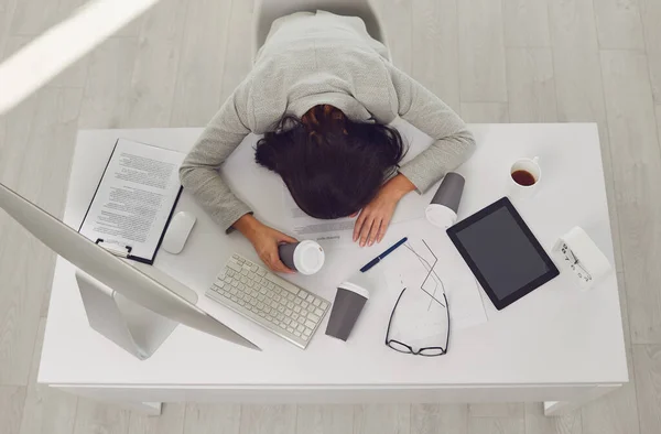 Tired business woman lies asleep at the desk workplace in the office. — Stock Photo, Image